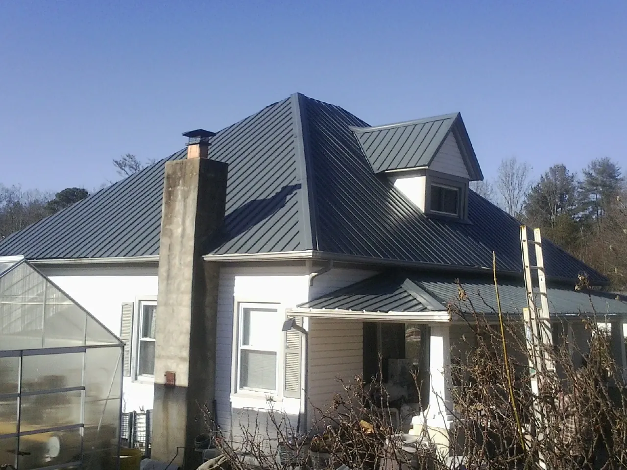 Dark blue standing seam metal roof on a white farmhouse with dormer — Slate & Tile Roof Repair by Roofing Brothers in Valhalla