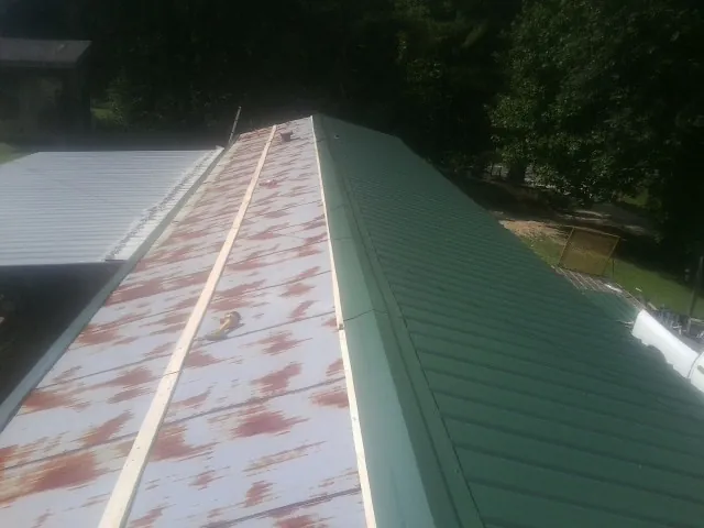 Old rusted panels beside newly installed green metal roofing — Wind Damage Roof Repair by Roofing Brothers in Valhalla