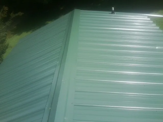 New green metal panels meeting at the ridge of a roof — Flat Roof Repair work by our crew in Valhalla