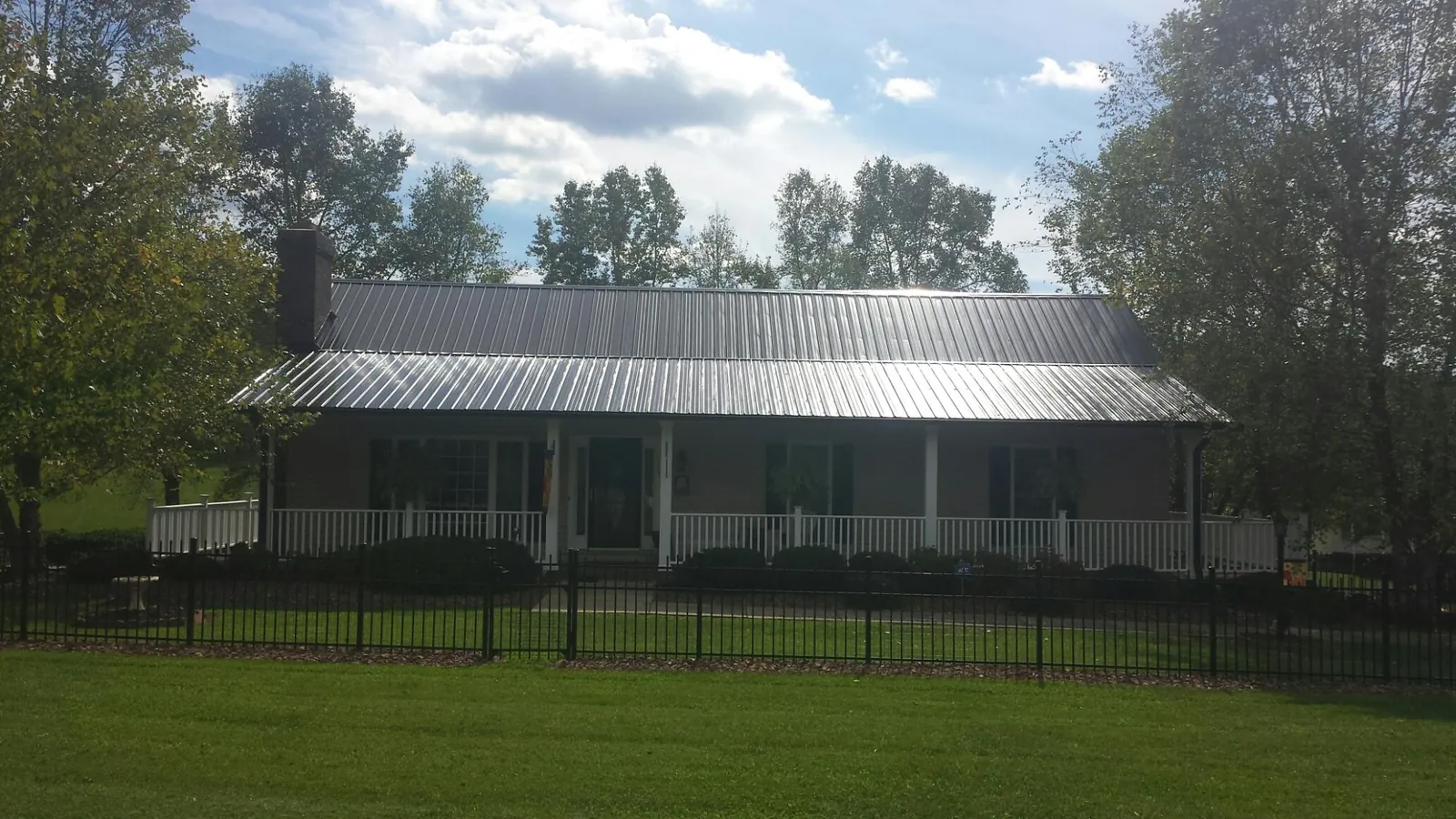 Gray metal roof on a brick ranch with a full width front porch — Gutter Guard Installation work by our crew in Valhalla