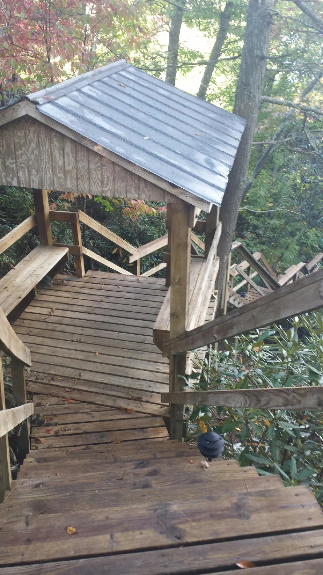 Metal roofed shelter over wooden steps on a wooded walkway — Skylight Repair & Installation work by our crew in Valhalla